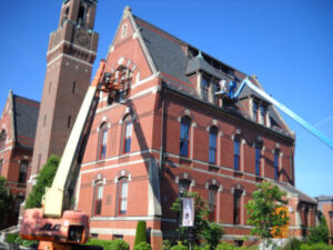 men paint exterior of brick cathedral